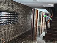 El pasillo interior de ladrillo tras la puerta de cristal, con una flecha verde que señala hacia el fondo.