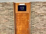 La puerta de madera de Aether, con el sigilo iluminado sobre el marco.